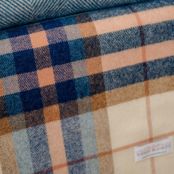 Stack of folded flannel fabrics in various patterns and colours with the Falmouth Blue & Ivory Check Shetland Wool Blanket