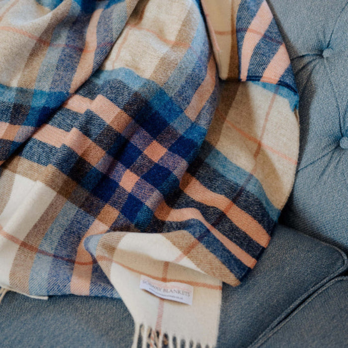Falmouth Blue & Ivory Check Shetland Wool Blanket with fringes draped over a blue sofa
