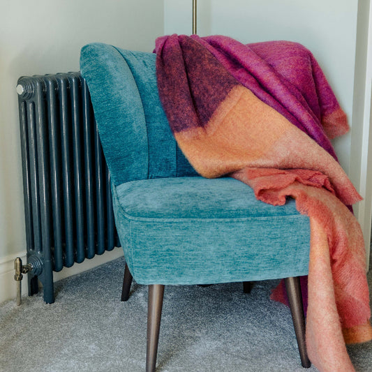 Blue chair with the colourful pink, plum and orange Fuchsia Mohair Throw blanket draped over it.