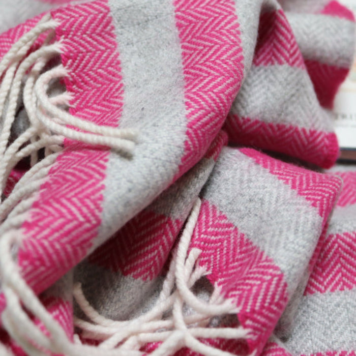 Georgina Stripe Cashmere Mix Baby Blanket a bright pink and soft grey striped blanket with tassels on a white surface