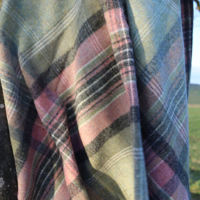 Green Kintyre Check Shetland Wool Throw draped over a tree branch with a scenic background