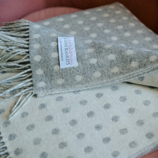 Folded grey and white spotted throw with a visible Solway Blankets label on a soft chair
