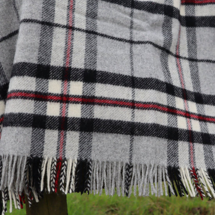 Grey Thompson Tartan Pure New Wool Blanket with fringes on a wooden fence in a field