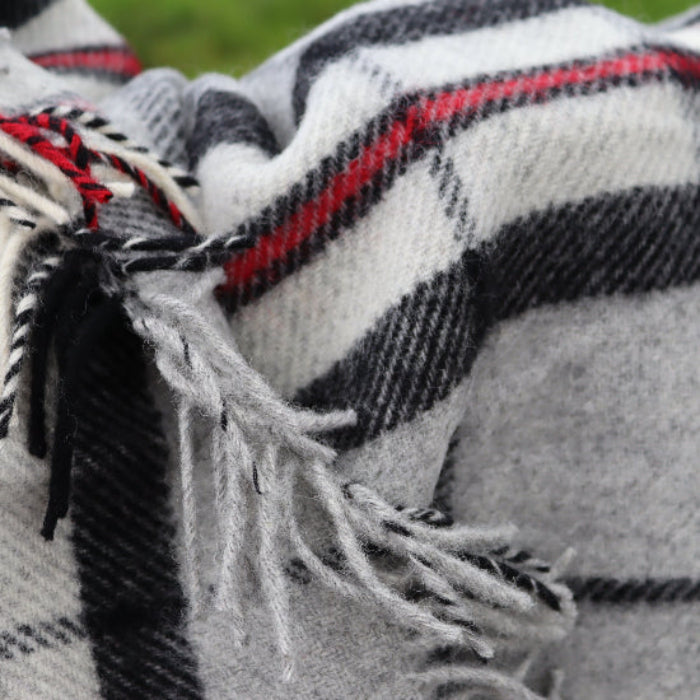 Close-up of the Grey Thompson Tartan Pure New Wool Blanket a plaid blanket with fringes in grey, black, red and white