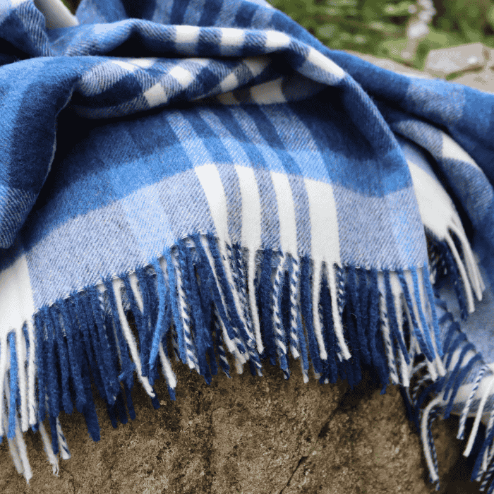 Blue checked lambswool throw with fringe folded over rocks