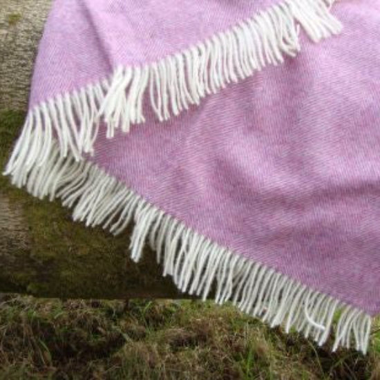 Heather Herringbone Shetland Wool Blanket Throw with white fringe draped over a log on grass