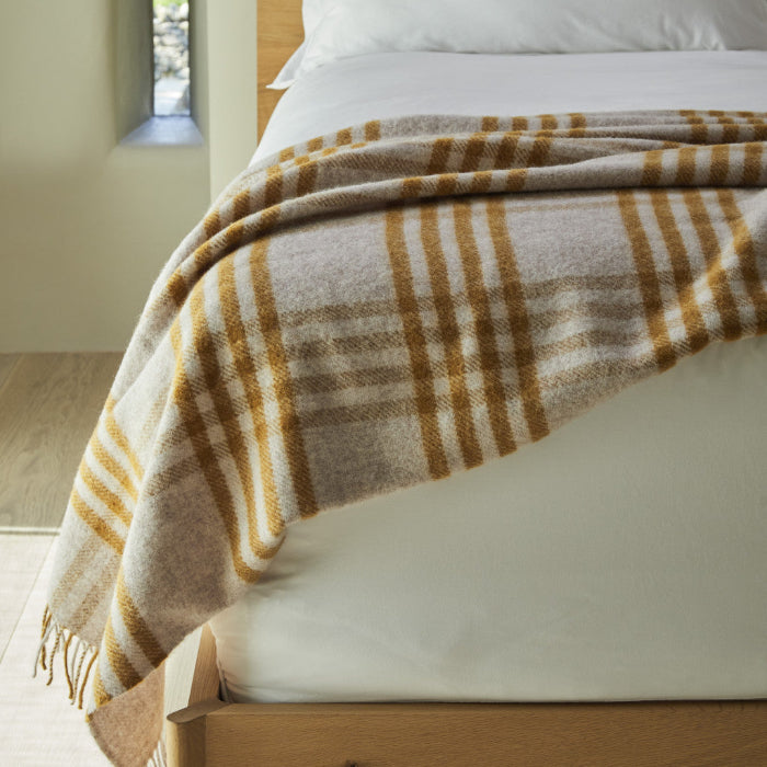 Extra large mustard and oatmeal checked wool blanket draped over a white furnished bed