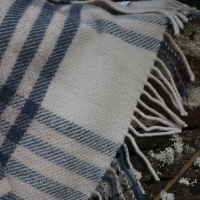 Plaid blue wool blanket with fringes on a stone wall 