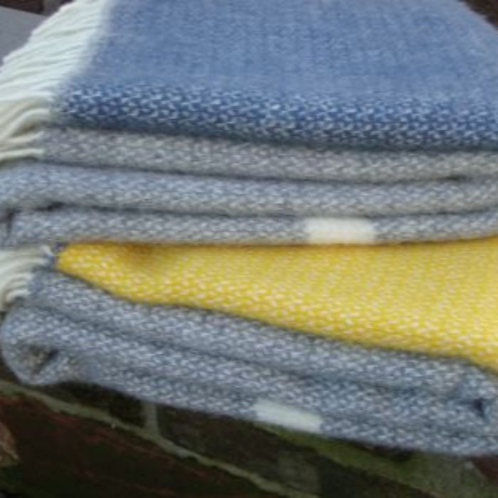 Stack of folded blankets in blue, grey, and yellow on a rock wall.