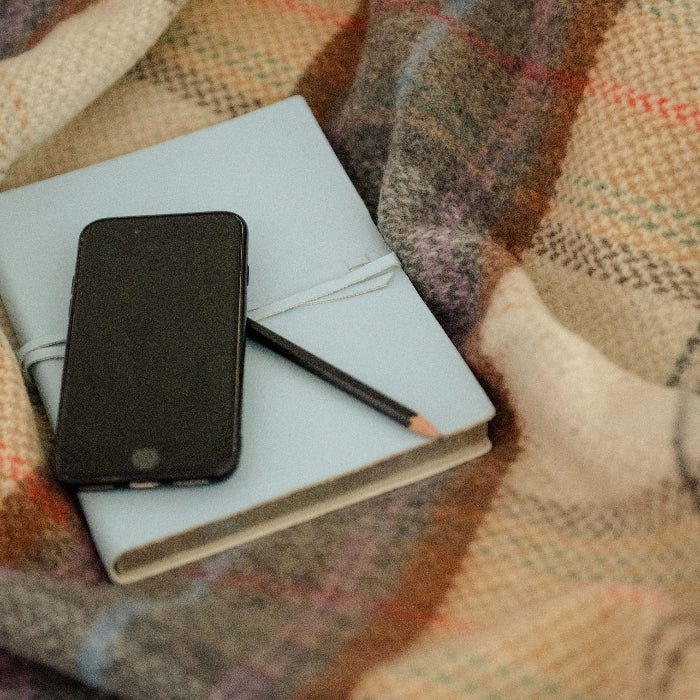 Phone and notebook on a plaid cashmere throw 