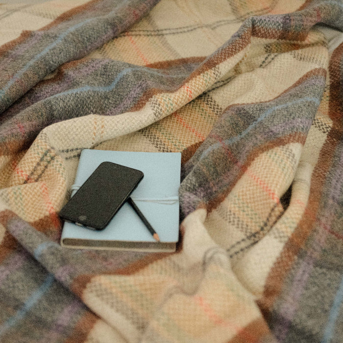 Phone and notebook on a plaid cashmere throw