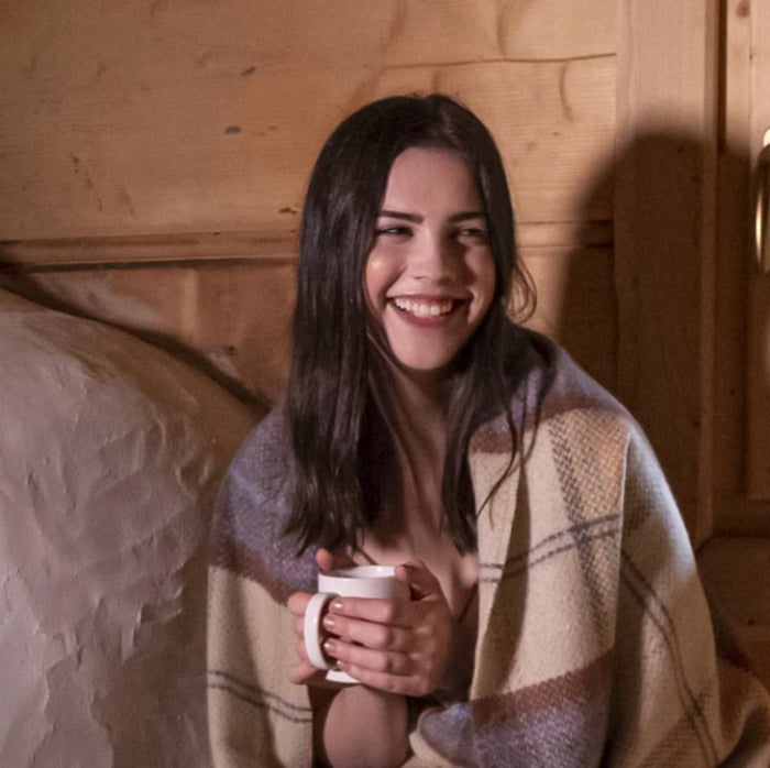 Woman wrapped in a cashmere throw holding a mug