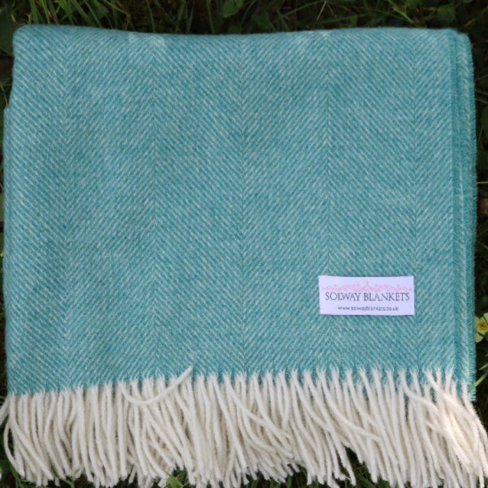 Jade Green Herringbone Shetland Wool Throw blanket with white fringe on grass