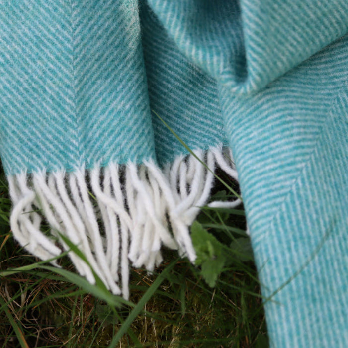 Jade Green Herringbone Shetland Wool Throw with white fringe on grass