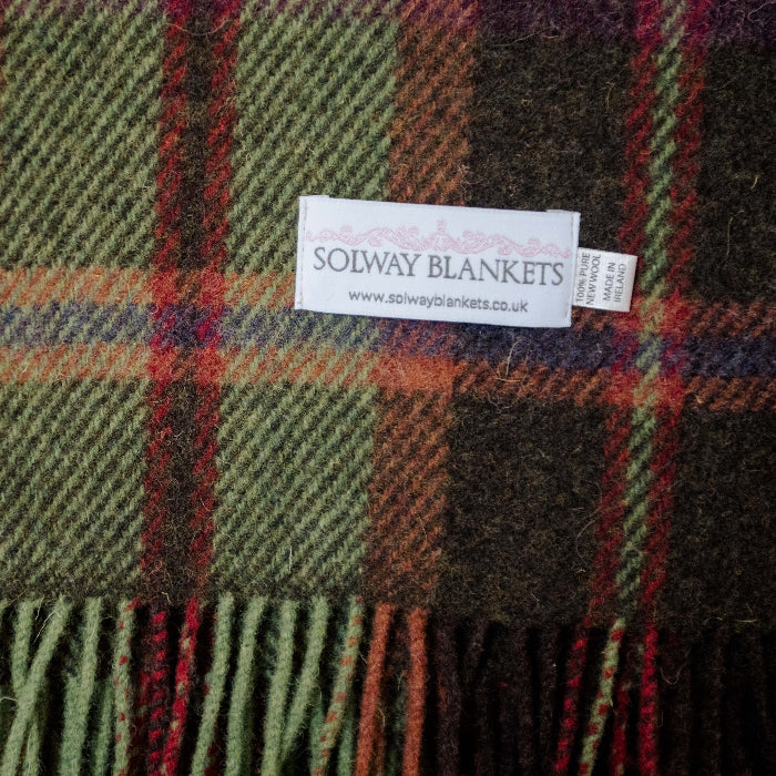 Close up of a plaid wool blanket with colourful fringe, featuring a Solway Blankets label