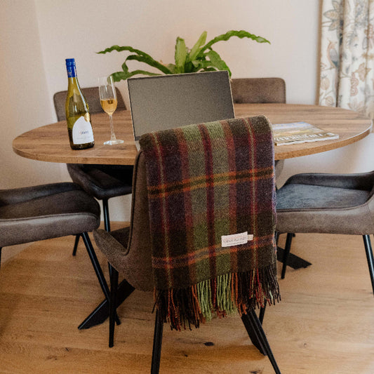 Dining room with a table, chairs, plant, wine and a glass with a plaid wool blanket draped over a dining chair