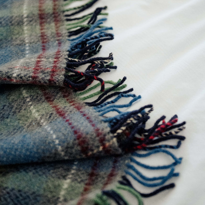 Close up plaid throw with fringes on a white surface