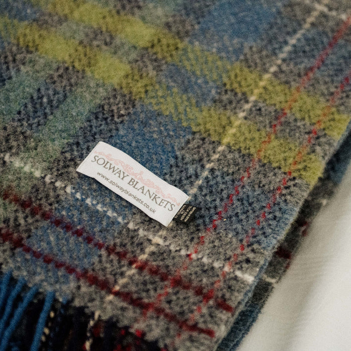 Close up plaid throw with a visible Solway Blankets label on a white background