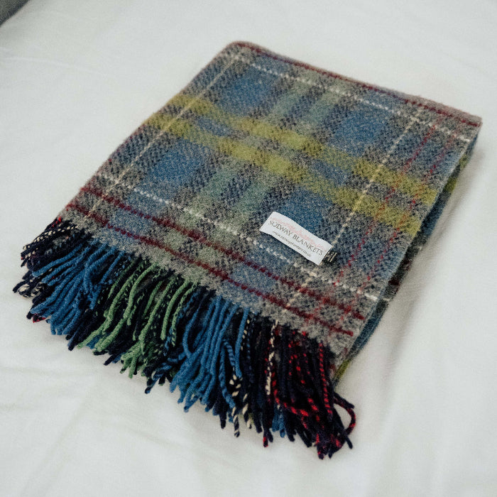 Folded Plaid throw with colorful fringes on a white surface