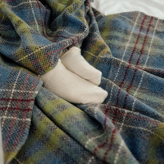 Plaid throw draped over a white surface with feet