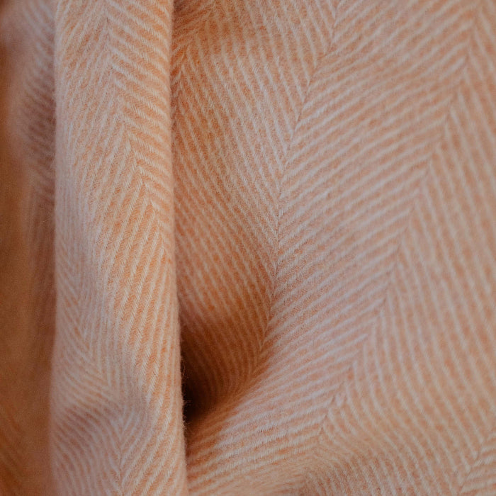 Close-up of textured peach  throw - the Mango Sorbet Shetland Wool Herringbone Blanket with a herringbone subtle pattern