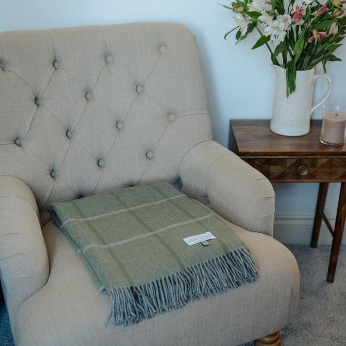 Soft sage green Scottish cashmere blanket folded on a cream upholstered armchair
