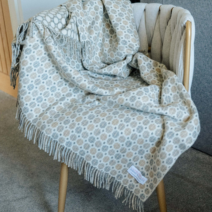 Patterned throw blanket draped over a chair with a neutral background