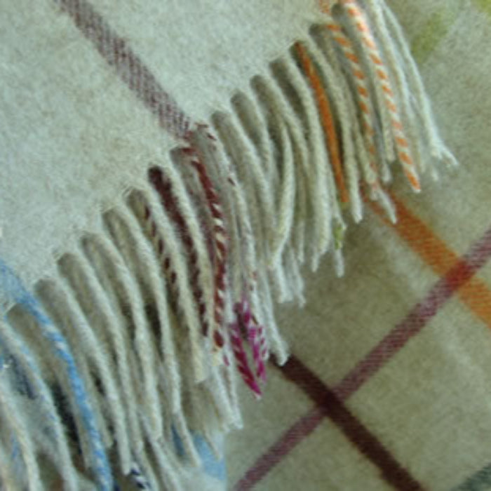 Close up of a multicoloured merino lambswool blanket with fringe