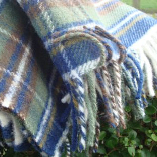 Muted Blue Stewart Tartan Plaid wool blanket with fringes on a green background