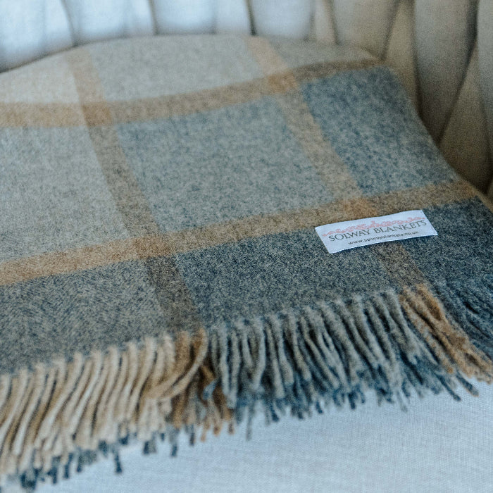 Natural plaid blanket with fringes folded on a chair, featuring a Solway Blankets label.