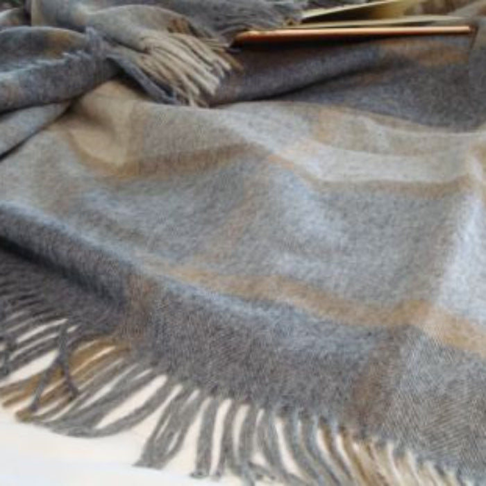 Natural grey and beige checkered blanket with fringes on a white surface