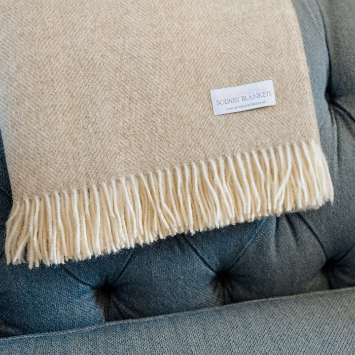 Beige Natural Herringbone Shetland Wool Blanket with a Solway Blankets woven label draped over a sofa