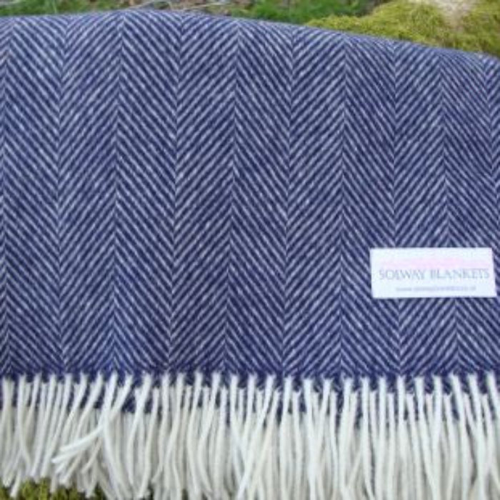 Navy blue herringbone patterned blanket with white fringes and a visible Solway Blankets label, set against a natural background.