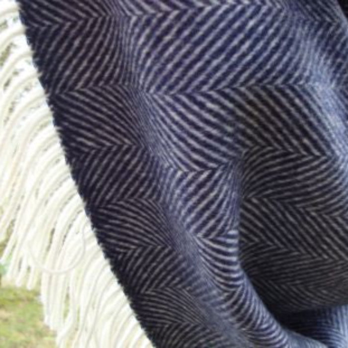 Close up of a navy blue herringbone patterned throw outdoors.