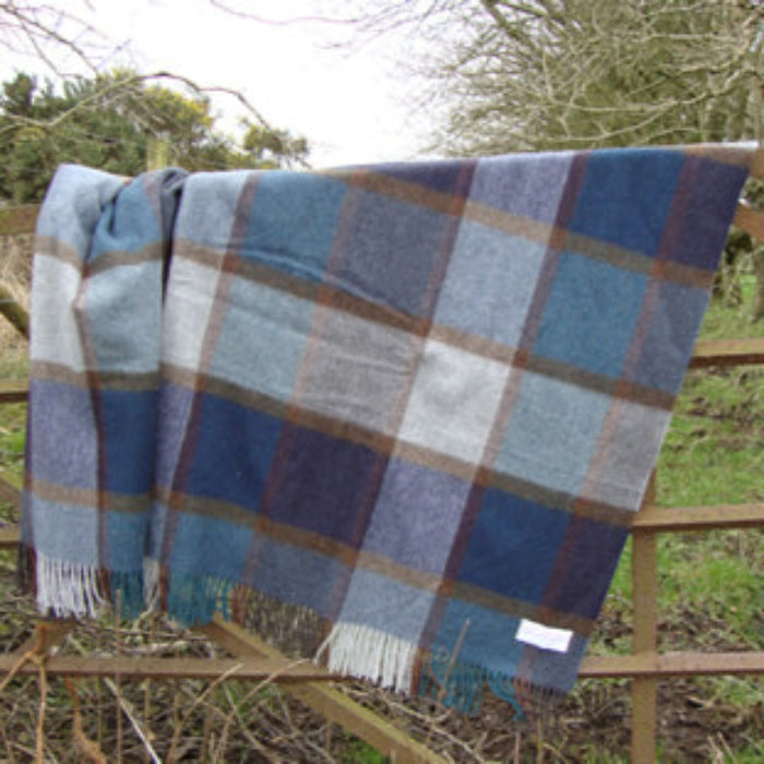 Blue plaid blanket draped over a wooden fence with a natural background