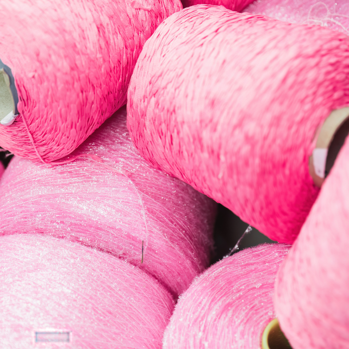 Close-up of pink yarn spools with a soft focus background, ready to be used on traditional weaving machines for blankets