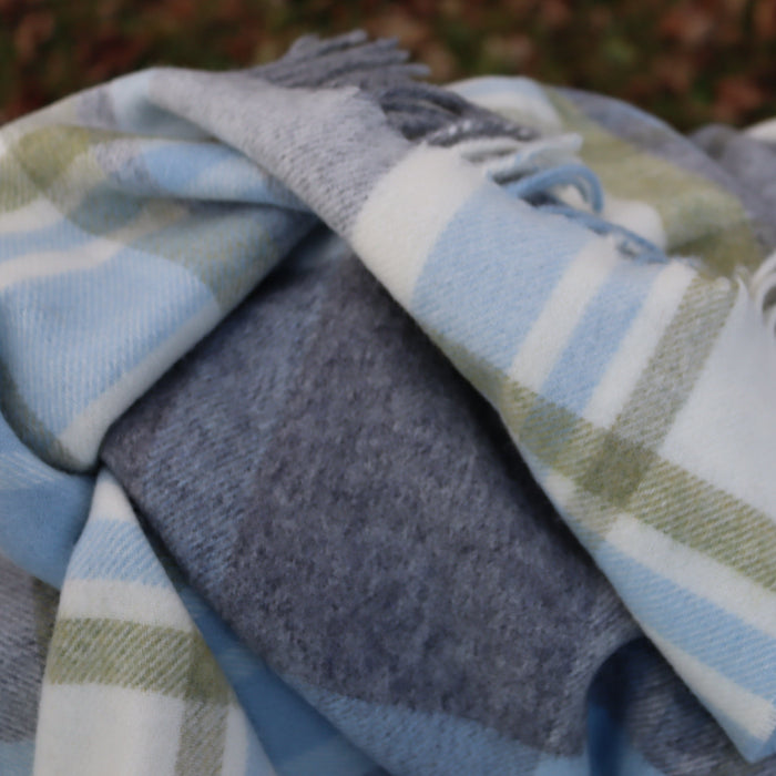 Close up plaid duck egg blue, grey and green blanket throw on a blurred background
