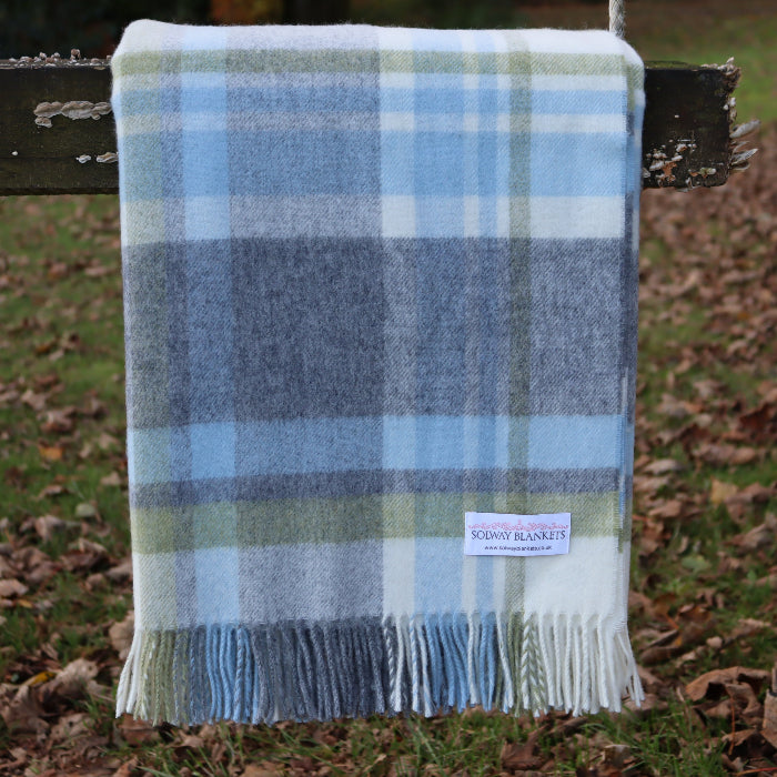 Plaid duck egg blue, grey and green blanket throw with fringes on a wooden swing outdoors