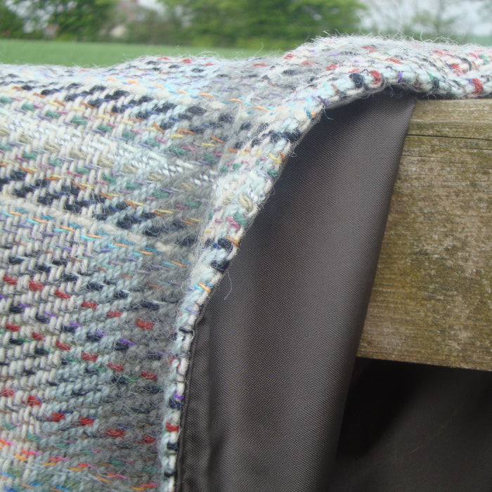 Close-up of a textured recycled fabric covering a wooden fence with a blurred natural background