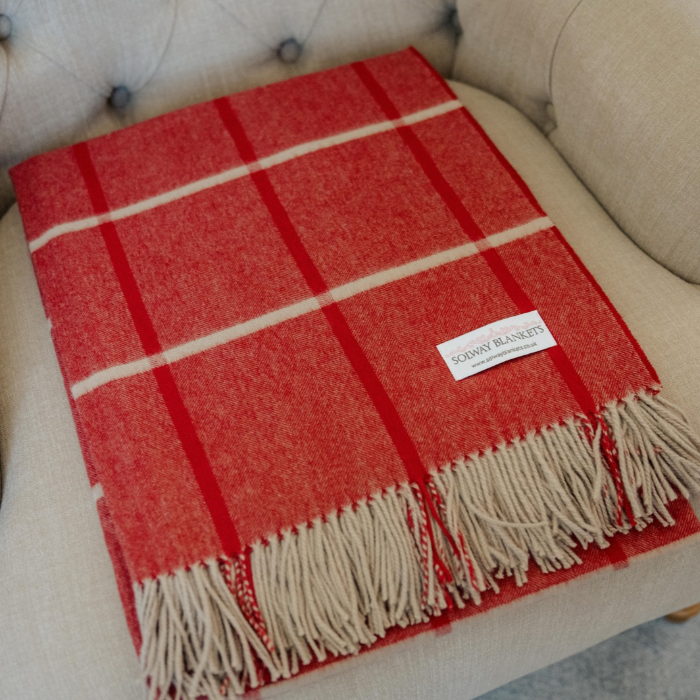 Folded pure cashmere throw in vibrant red with a red and french grey windowpane over check and beautiful twisted fringe edge, on a linen covered button back arm chair