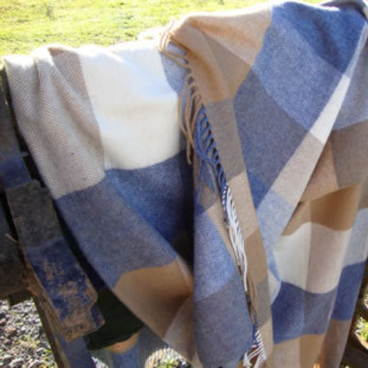 Denim, tan, sea, sand, blue and beige lambswool throw draped outdoors