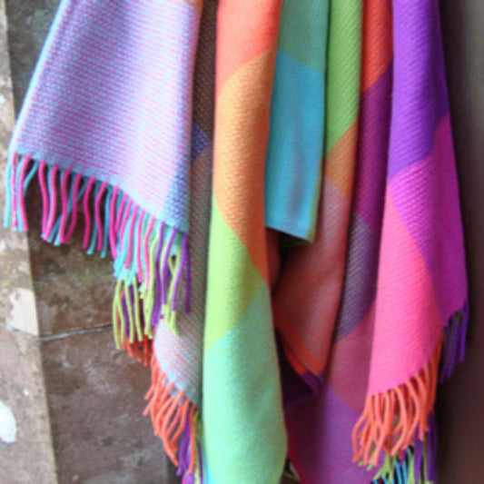 Colorful striped cashmere mix throw with fringe hanging on door