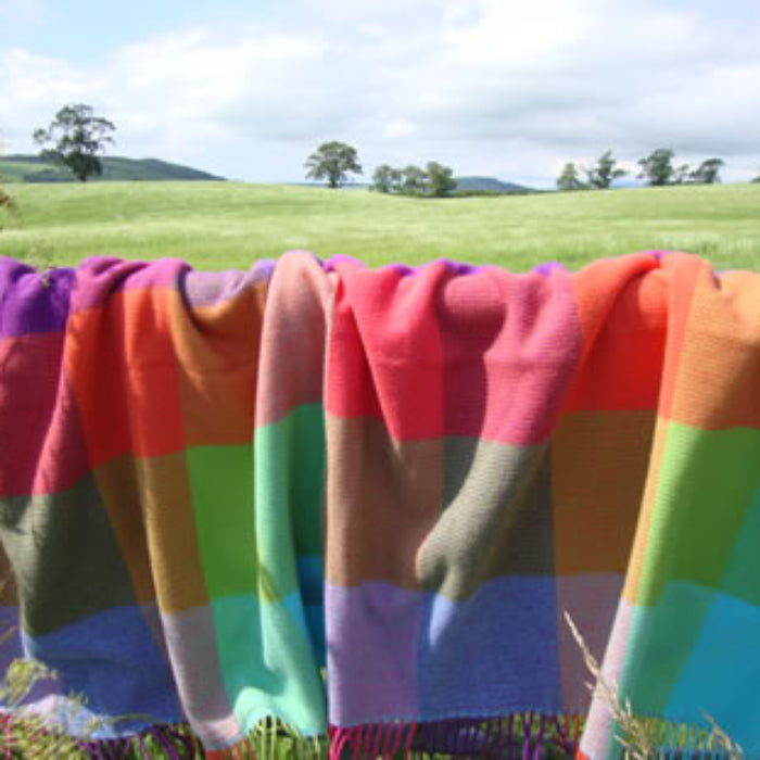 Colorful cashmere mix throw hanging over a gate against a natural background