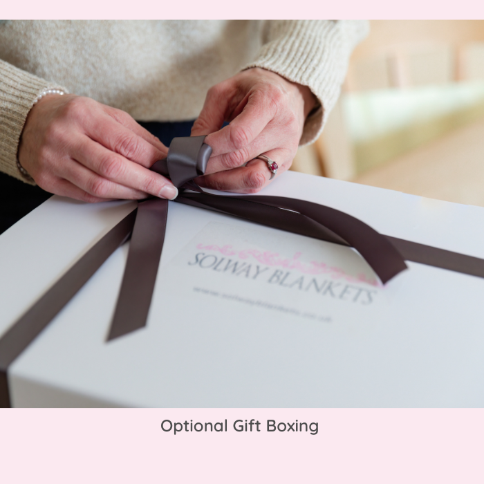 Hands tying a satin ribbon on a Solway Blankets gift box – showcasing thoughtful presentation and elegant, British-made gifting.