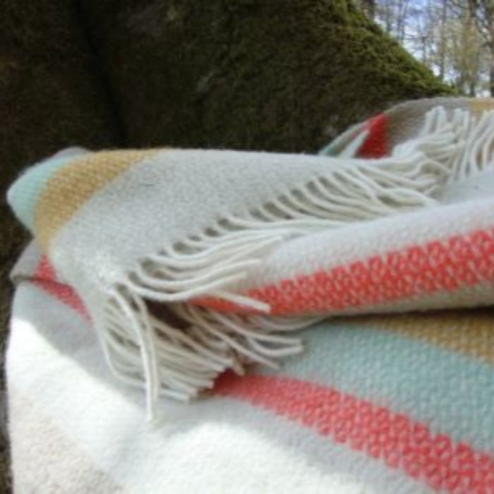 Woven striped wool blanket with colorful stripes and fringes on a natural background