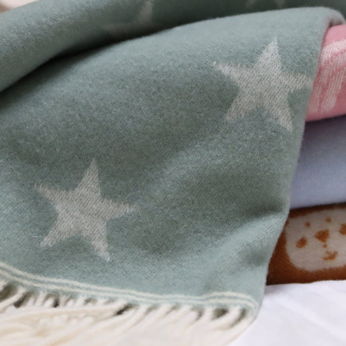 Stack of soft baby blankets with star patterns on a white surface the Star Sea Green Merino Wool Baby Blanket