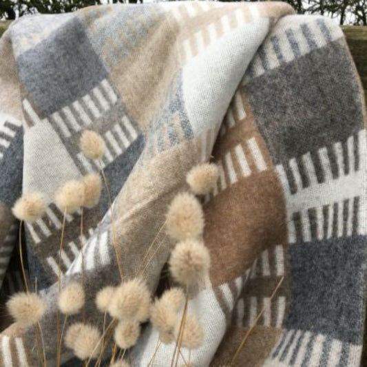 Camel, slate grey and off-white plaid throw with dried plants in the foreground
