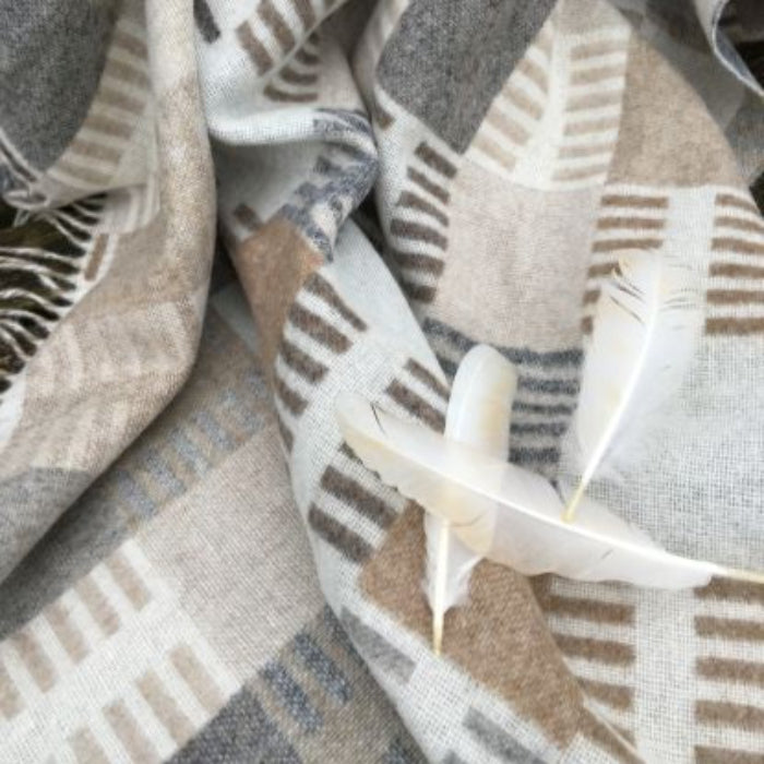 Close up of a patterned natural fabric throw with feathers on top