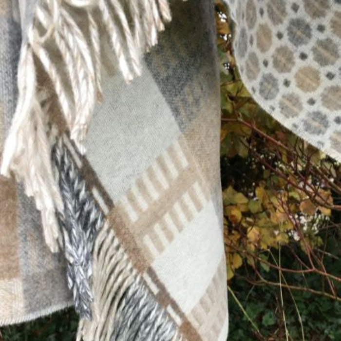 Plaid natural colored blanket with fringe draped over a tree branch
