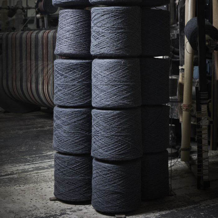 Stack of grey yarn bobbins in a textile mill setting